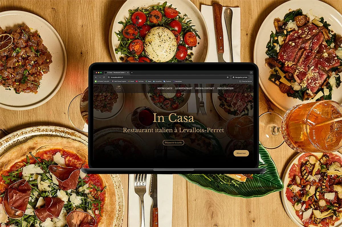 Mockup d'ordinateur portable présentant le site web du restaurant In Casa sur un fond de table de restaurant italien